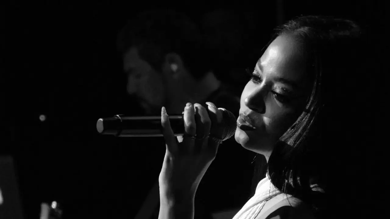 Black and white close-up of Carymel Rodríguez singing into a microphone