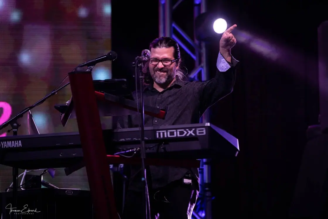 Esteban Rojas plays keyboards on stage under purple lights